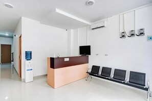 A reception area with a counter, a water dispenser, a flat-screen TV, and a row of computer monitors.