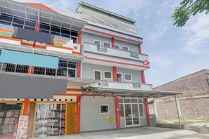 A multi-story building with a garage entrance, a storefront on the ground floor, and a balcony on the upper floors.