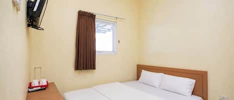 A single bed with white bedding, a wooden headboard, a small table with a red tray, a wall-mounted TV, and a window with brown curtains.