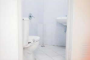 A bathroom with a toilet, a sink, and tiled walls. - Ava Guest House Magelang (Magelang)