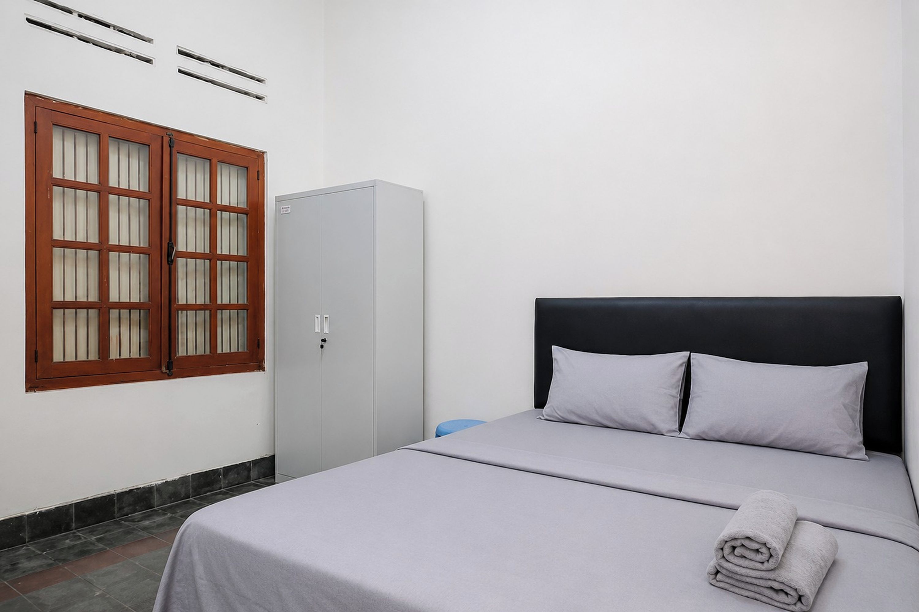 A bedroom with a bed, a wardrobe, and a window with blinds.