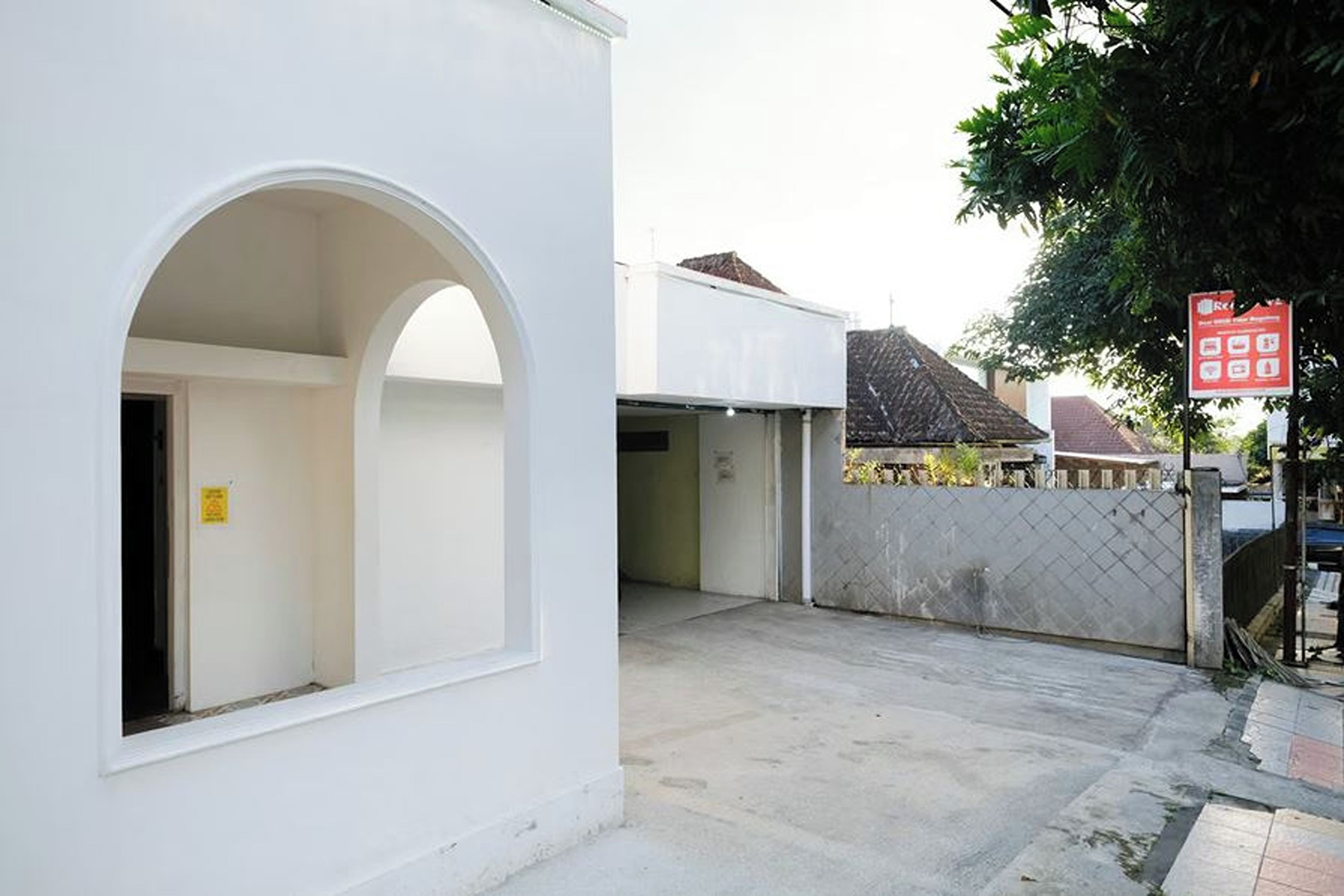 Un bâtiment blanc doté d’une grande porte en arc de cercle et d’une entrée fermée par un portail.