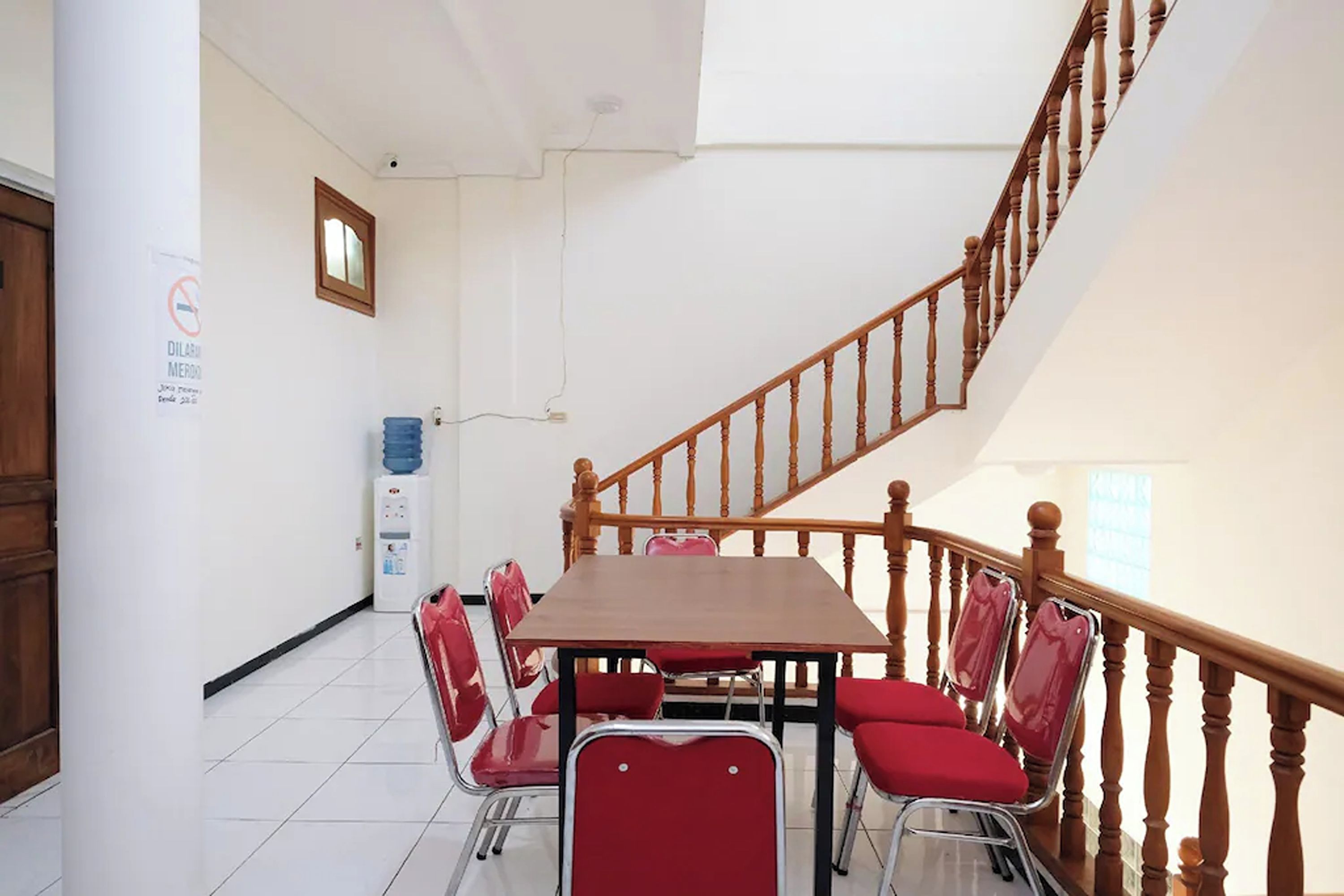 A conference room with a wooden staircase, white walls, and red chairs.