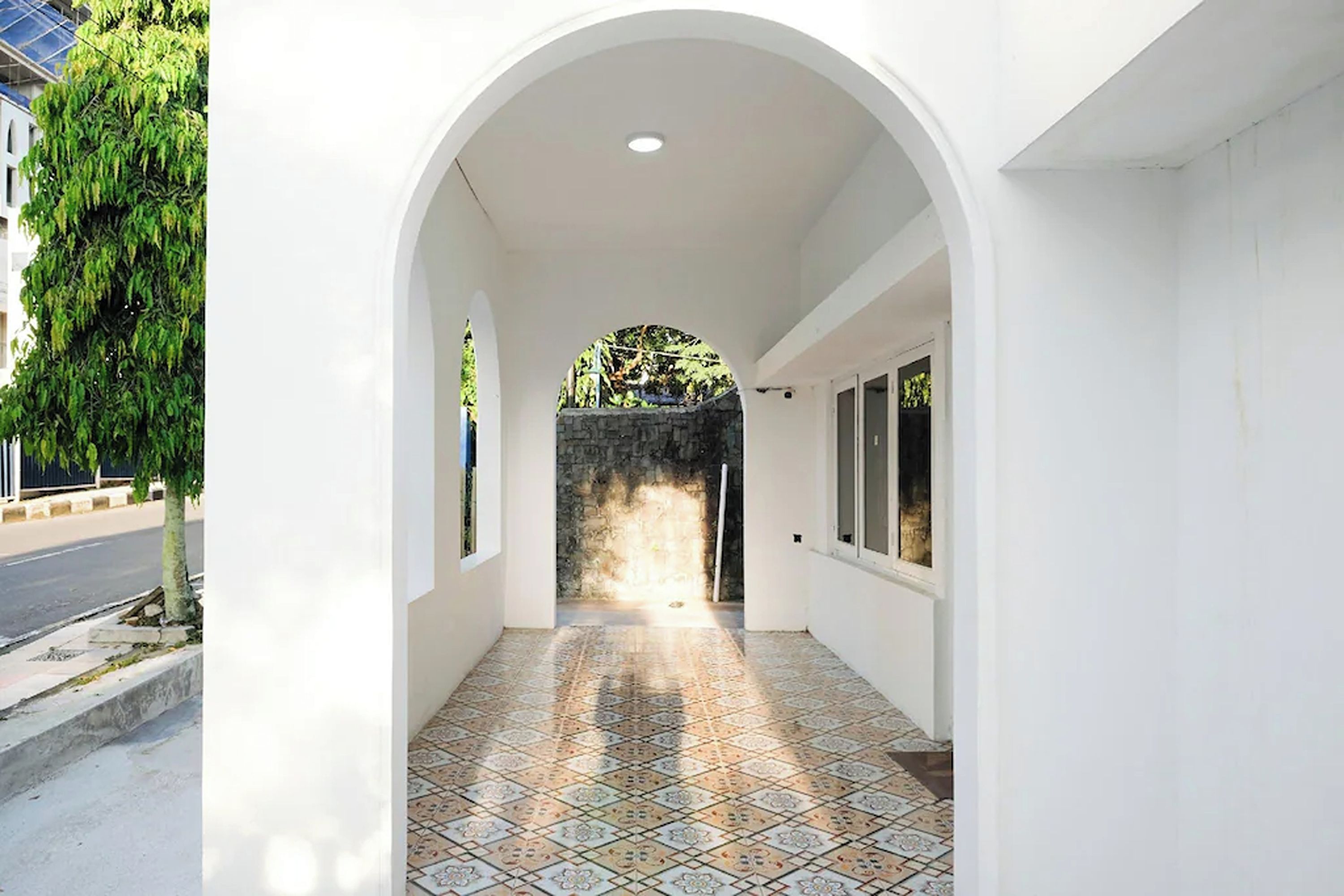 A corridor with a tiled floor, white walls, and an arched entrance.
