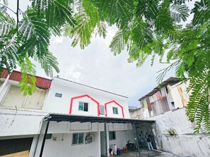 A residential area with a white building featuring a red outline, a covered garage, and a person standing near a wall.