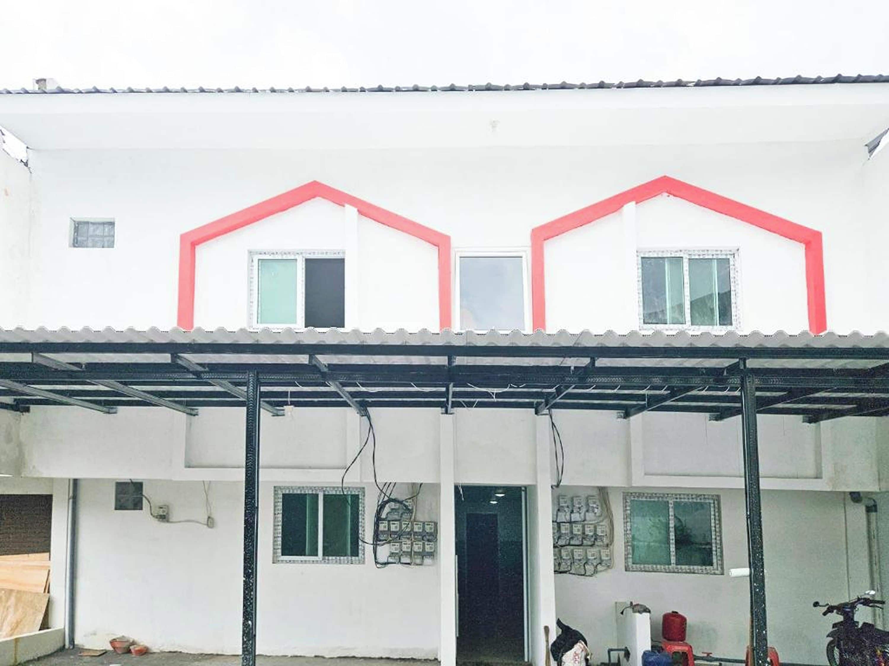 Un edificio de dos pisos con techo plano, un vestíbulo cubierto y una puerta visible.
