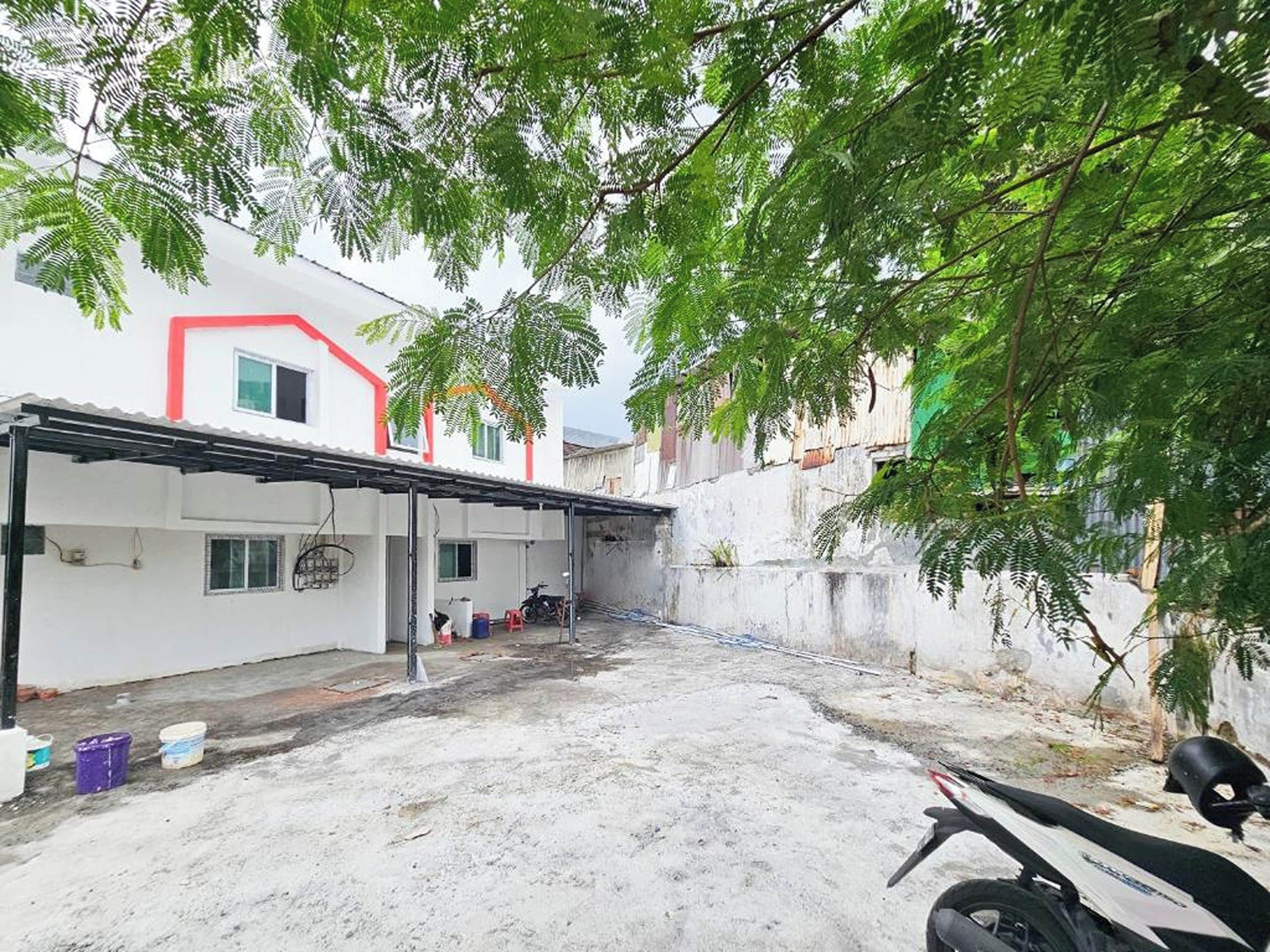 Una zona residencial con un edificio blanco, un espacio exterior techado y una motocicleta.
