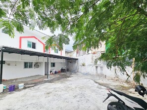 Zona residencial com um edifício branco, área externa coberta e uma motocicleta.