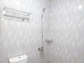 A bathroom with a toilet, a shower with a handheld showerhead, and a towel rack.