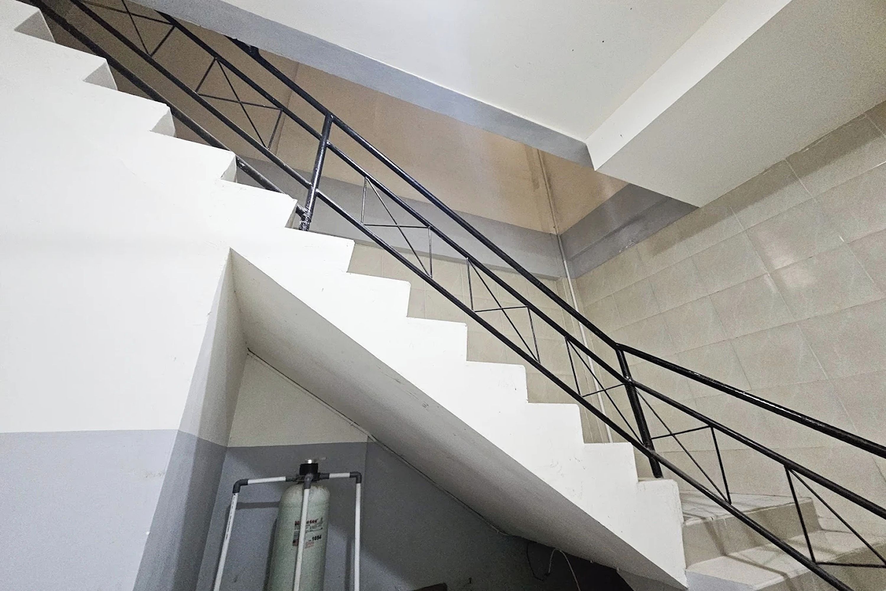 Un escalier doté d’une rampe métallique et d’un extincteur fixé au mur.