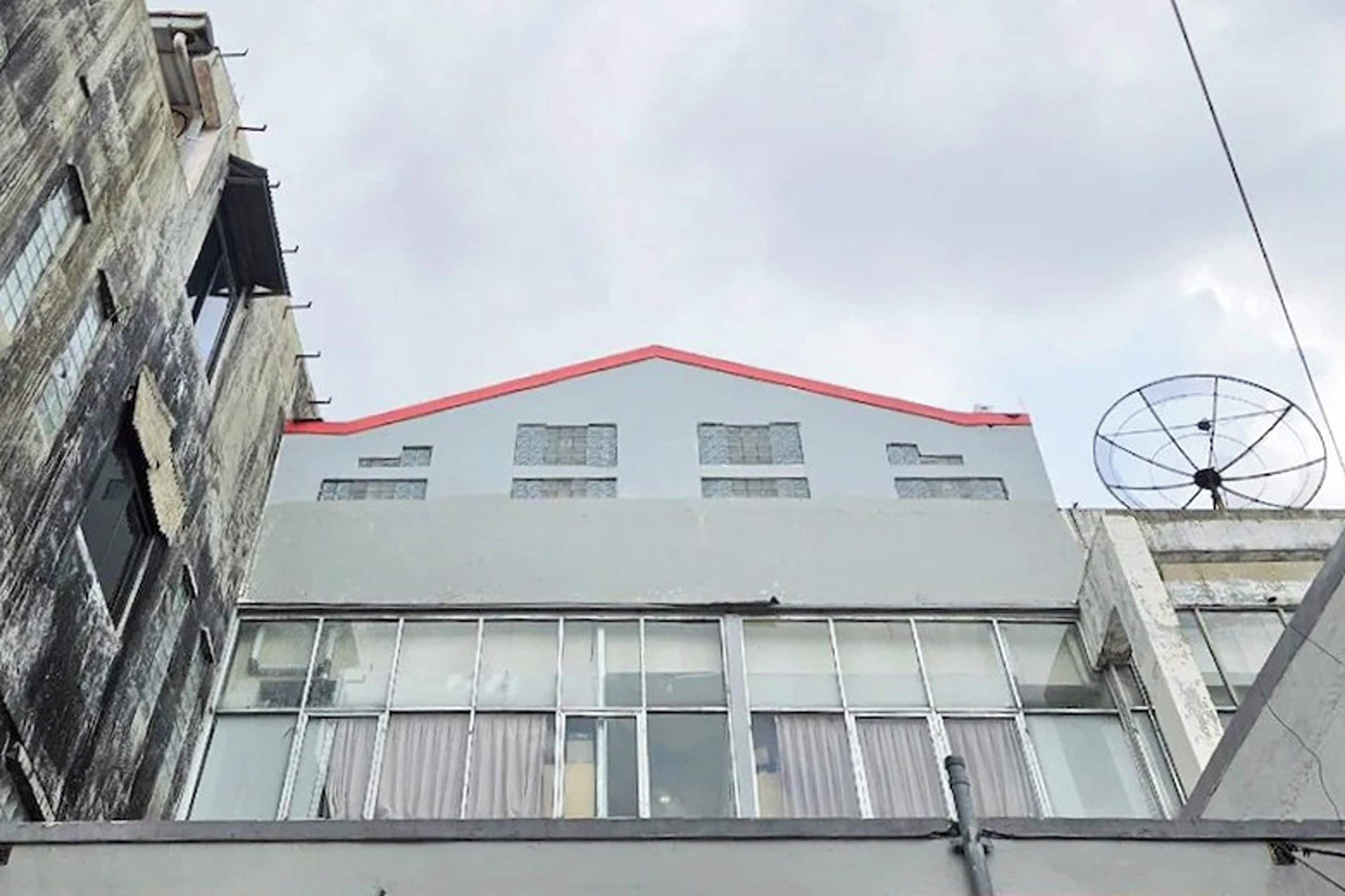 Un edificio con techo rojo, ventanas grandes y una antena parabólica.