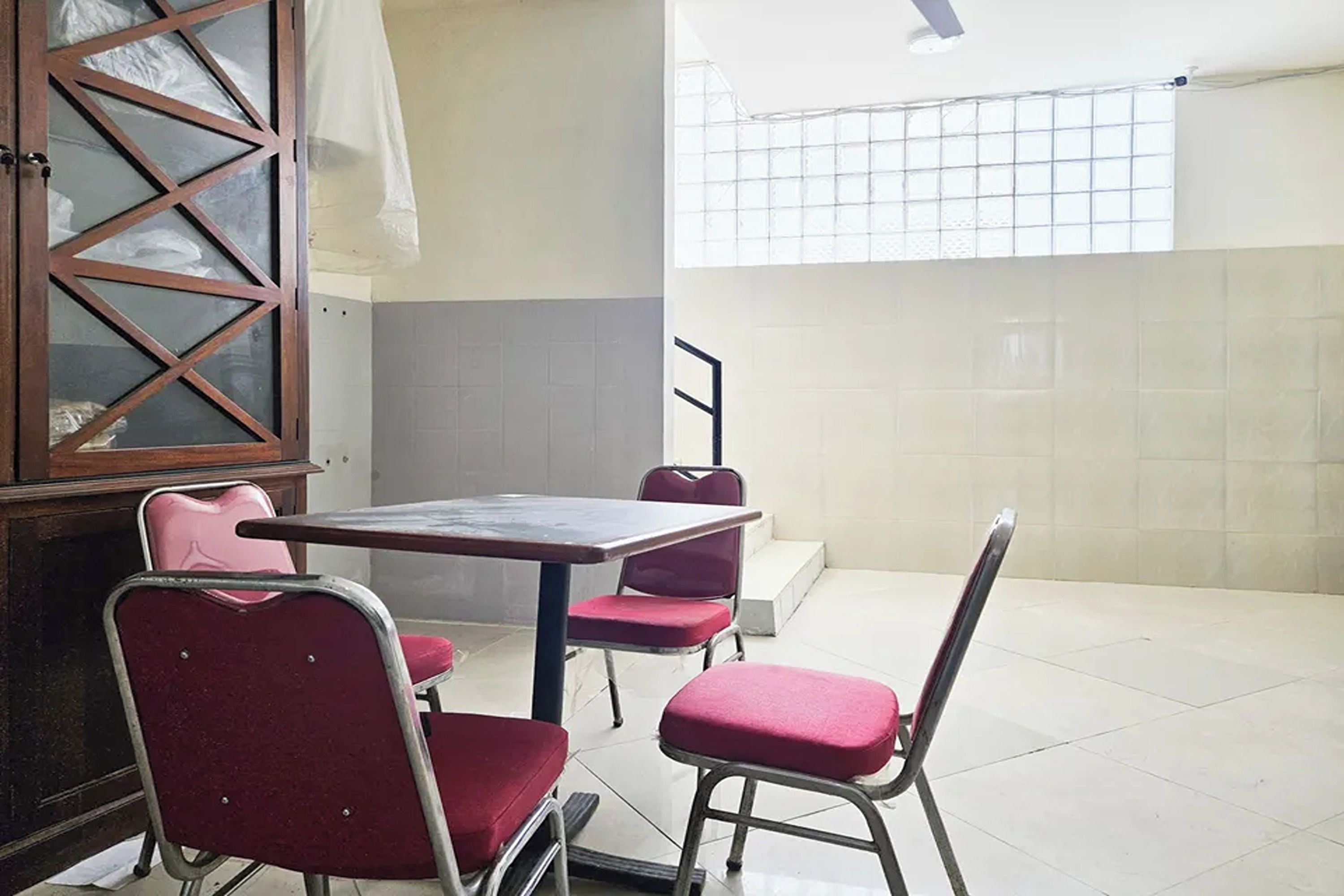 Une pièce comprenant une table et des chaises, un meuble et une fenêtre à carreaux.