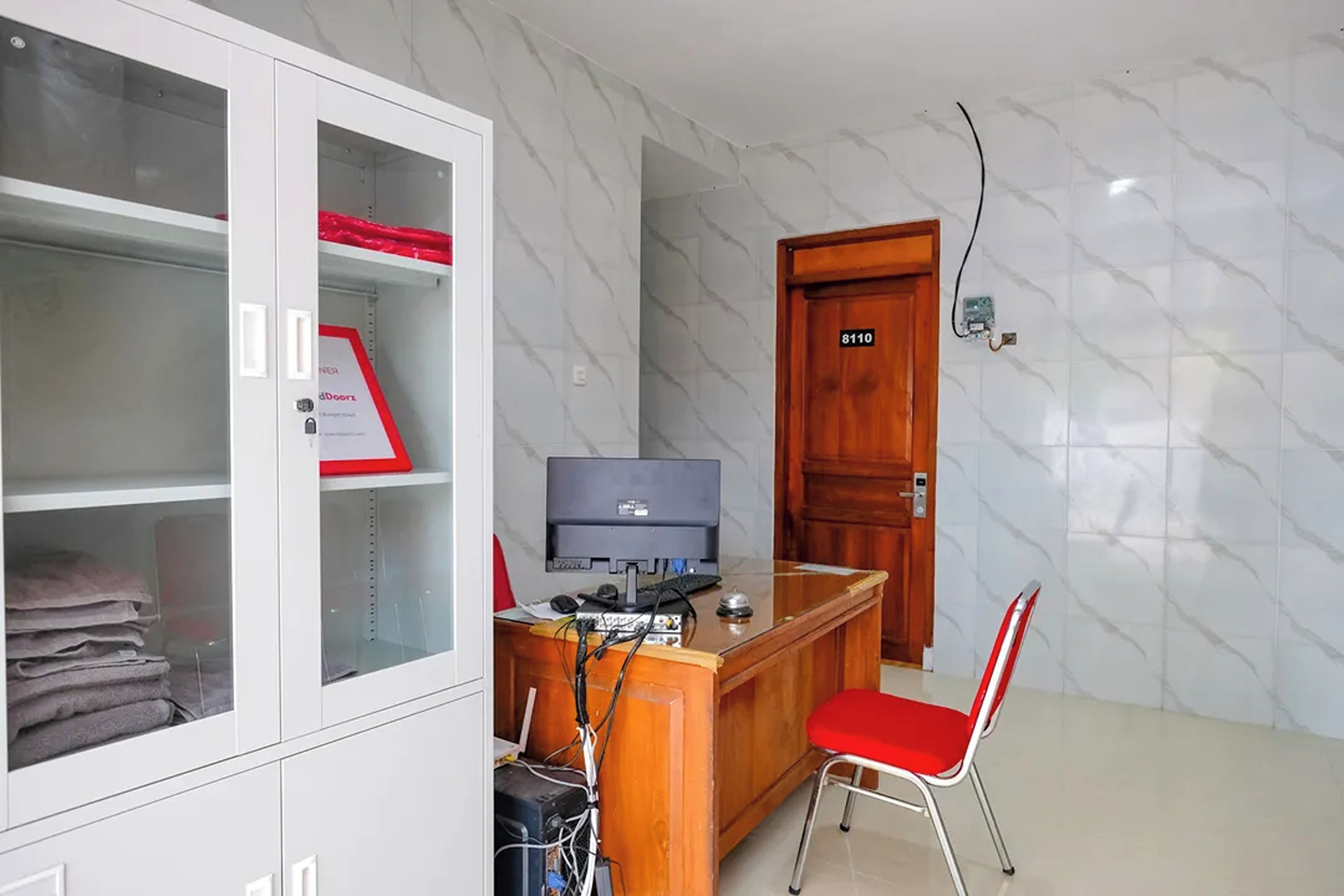 Quarto com escrivaninha, cadeira e armário com portas de vidro.