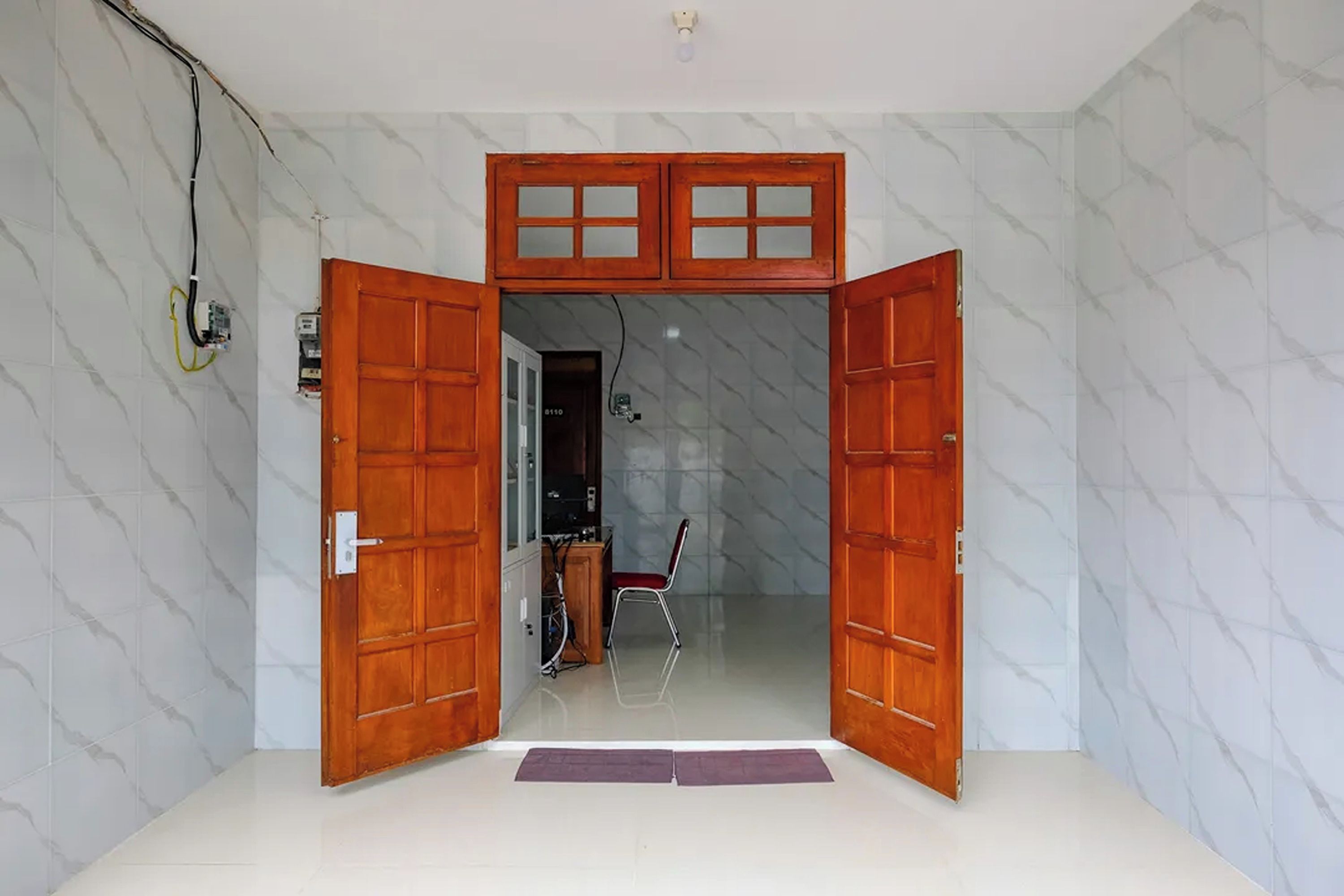 Quarto com porta de madeira que dá para um corredor.