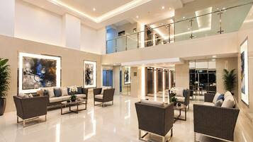 Un lobby amplio con techo alto, muebles modernos y obras de arte en las paredes.