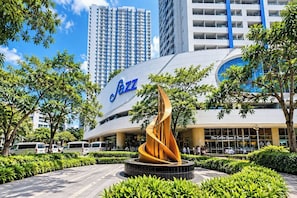 A modern building with a prominent 'Jazz' sign, surrounded by greenery and other buildings. - Jazz Residences (Makati)