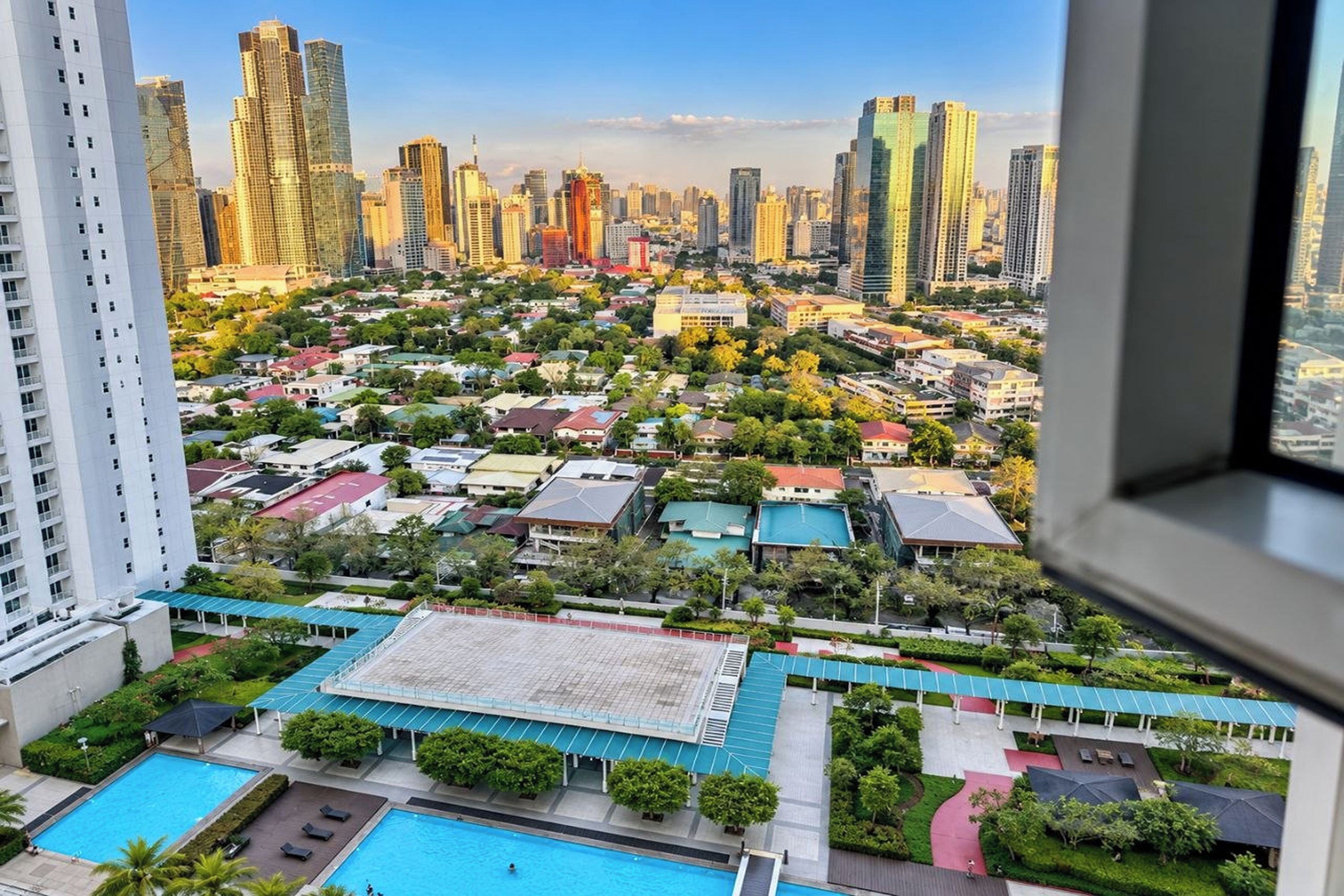 Un edificio de gran altura con vistas a un paisaje urbano, una piscina y un área exterior cubierta.