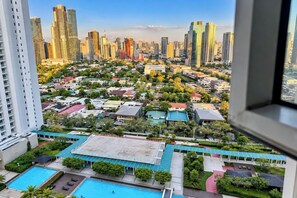 Un edificio de gran altura con vistas a un paisaje urbano, una piscina y un área exterior cubierta.