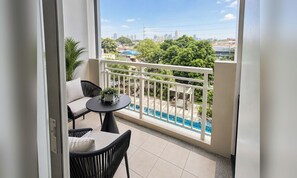 A balcony with a view of a cityscape, a pool, and a small table with chairs. - The Orabella Residences - Qc (Cubao) (Quezon)