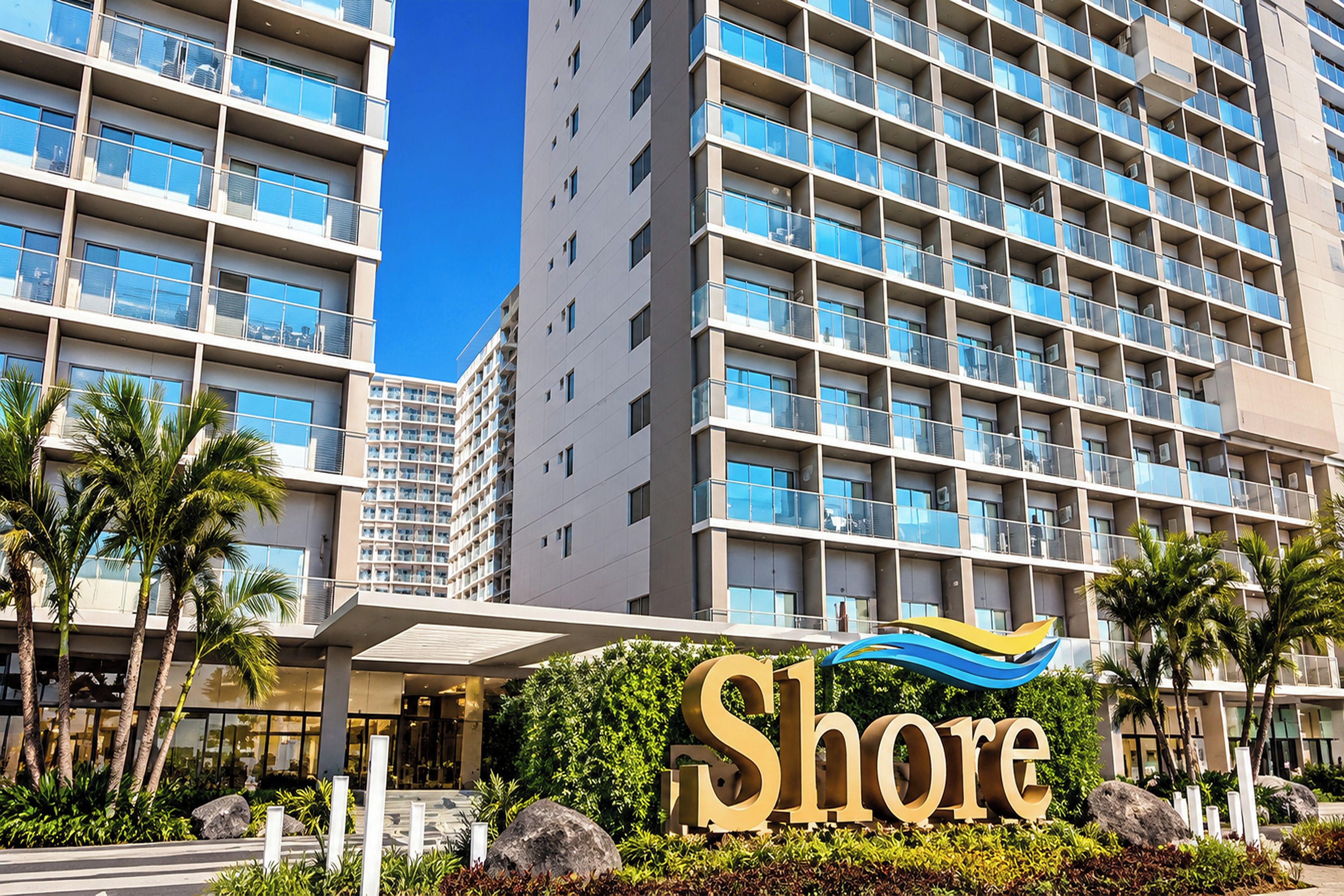 Un hôtel à plusieurs étages, reconnaissable à son grand panneau « Shore », qui présente une architecture moderne avec des balcons et une vue dégagée sur le ciel.