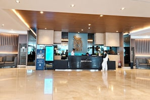 A hotel reception area with a marble counter, a large decorative wall, and a modern ceiling design. - Shore Residences Moa Pasay (Pasay)