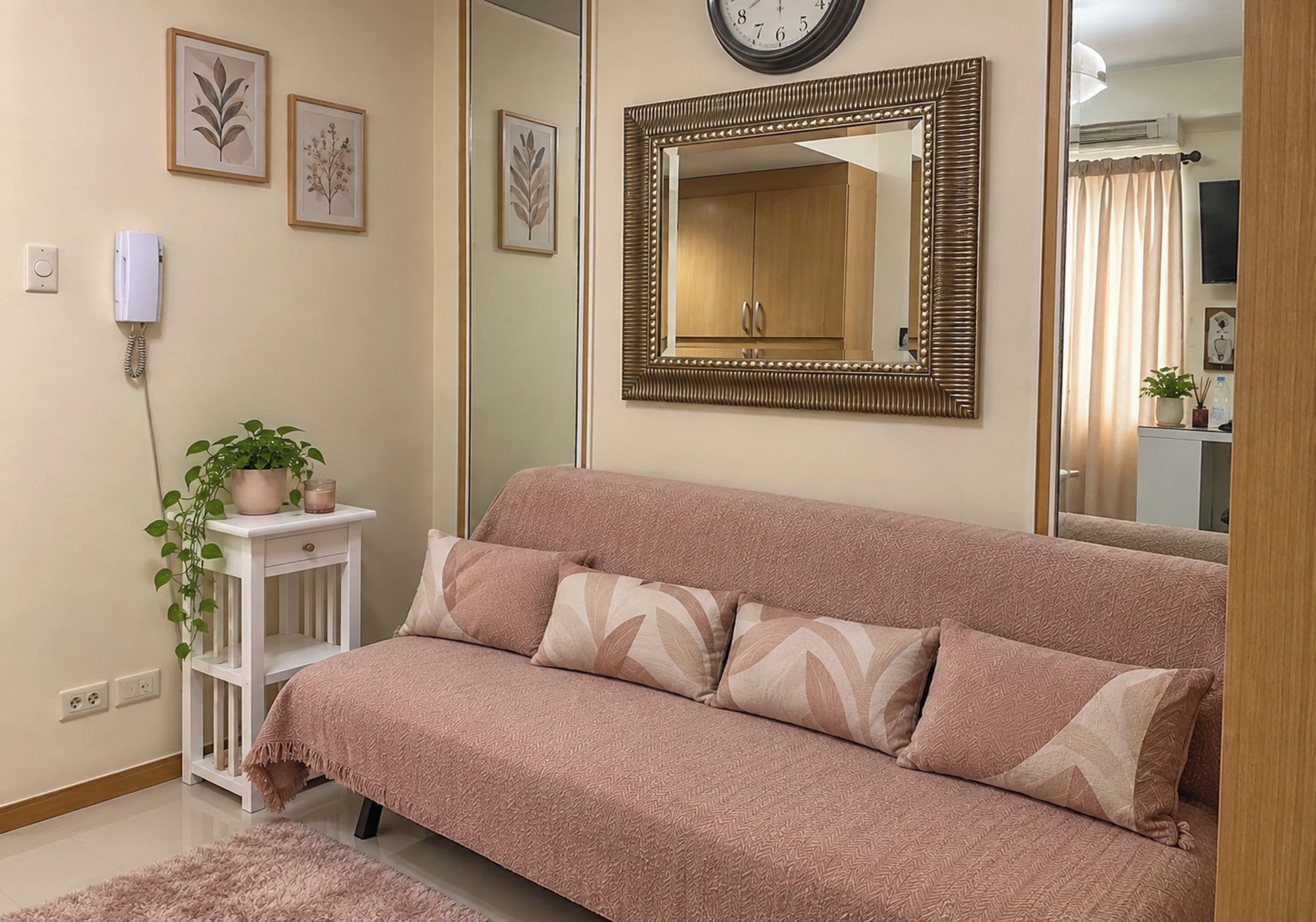 Une pièce comprenant un canapé, une table de chevet avec une plante, une horloge murale et un miroir.