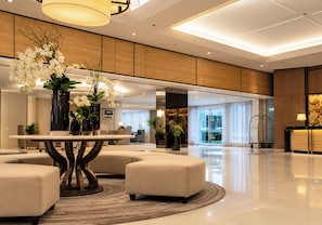 A modern lobby with a round table, seating, and decorative plants. - Shell Residences Cozy Staycation (Pasay)