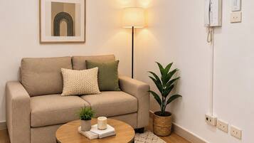 A living room with a sofa, a lamp, a plant, and a coffee table.