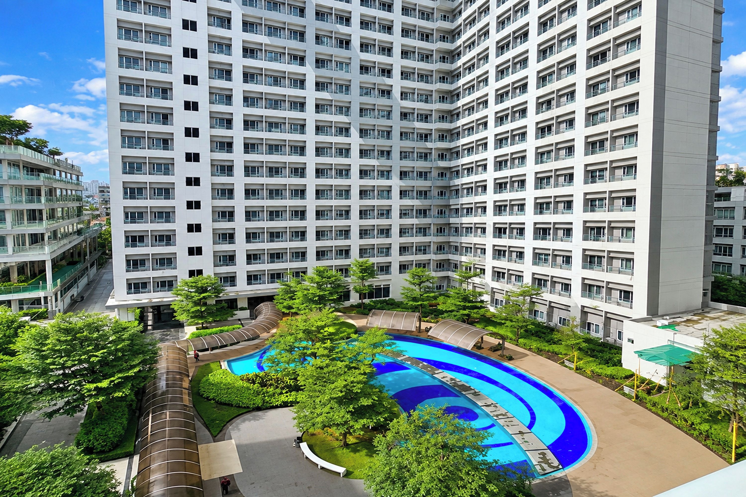 A high-rise residential building with multiple balconies, a central swimming pool, and surrounding greenery.