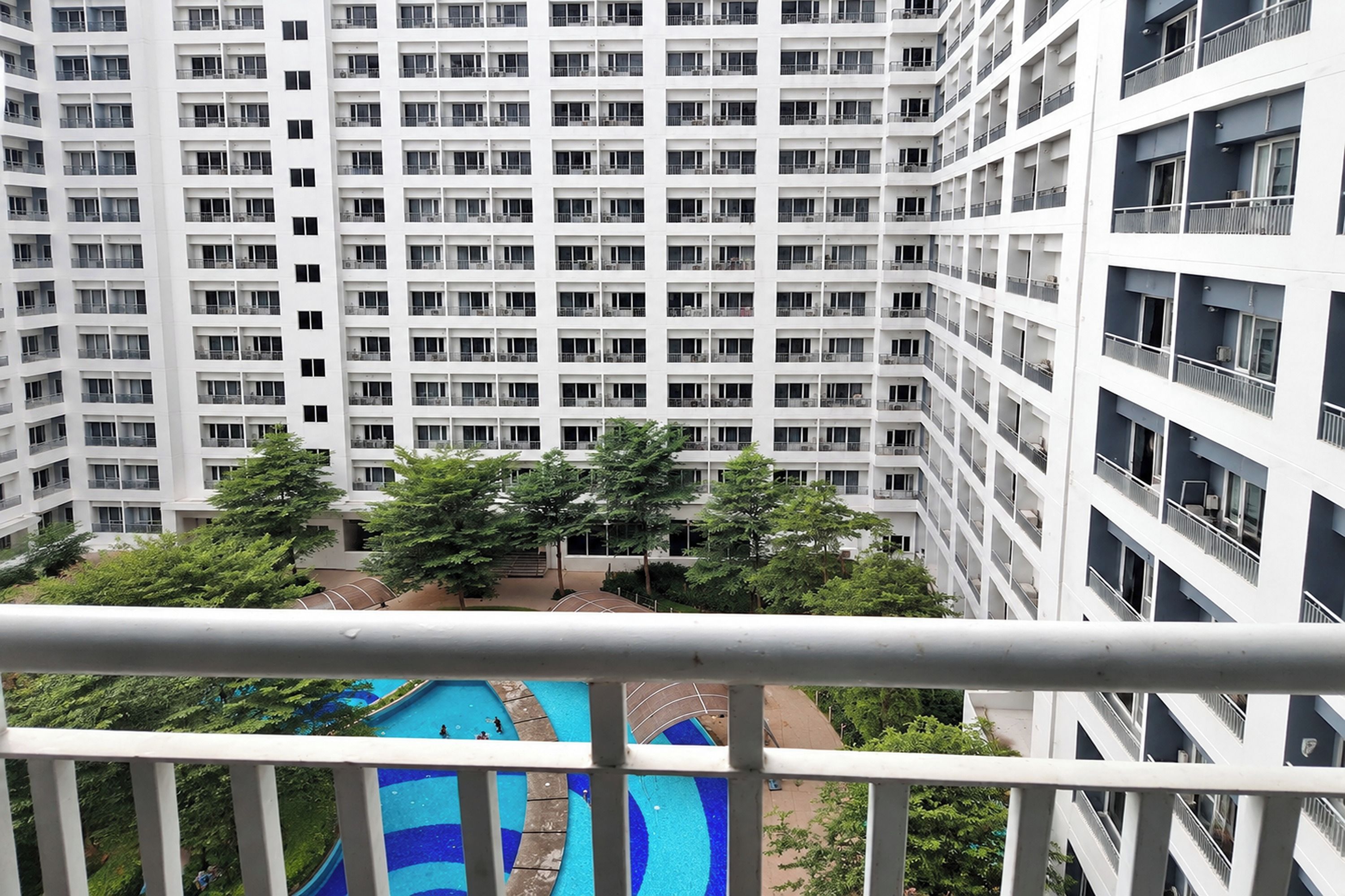 A high-rise building with multiple balconies and a swimming pool area.