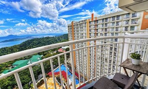 A high-rise building with balconies, a view of a mountainous landscape, and a body of water in the distance. - Tagaytay Prime Residences In Tagaytay City (Tagaytay)