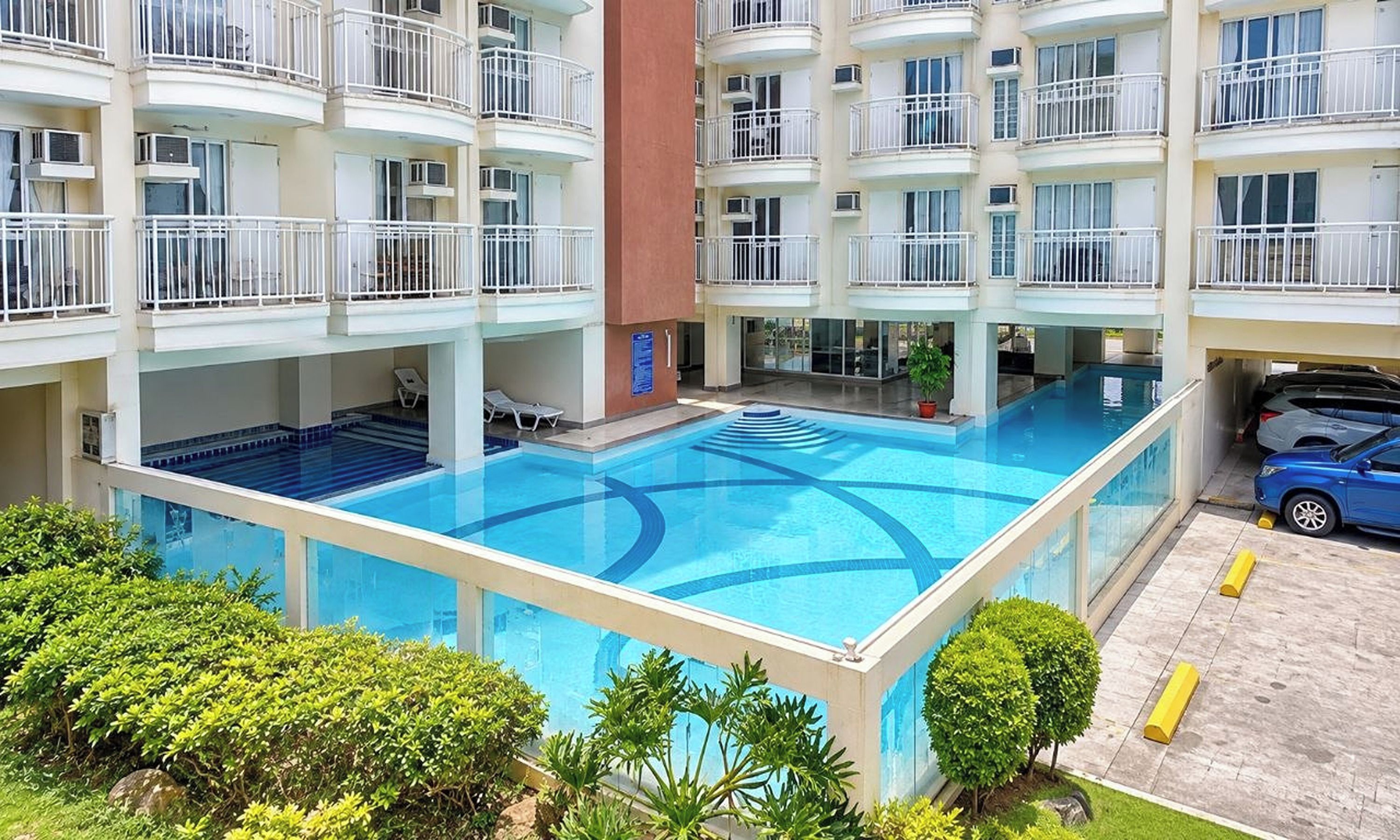 A multi-story hotel with a central swimming pool surrounded by balconies.
