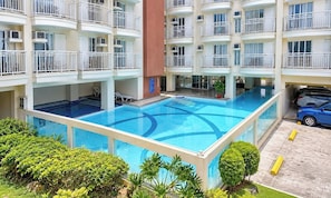 A multi-story hotel with a central swimming pool surrounded by balconies. - Tagaytay Prime Residences In Tagaytay City (Tagaytay)