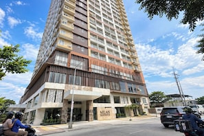 Un edificio de gran altura con varios balcones, una entrada destacada y un letrero que dice 'MILAN RESIDENZE'.