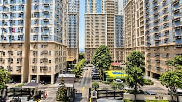 A high-rise residential building with multiple balconies, a gated entrance, and a clear sky.