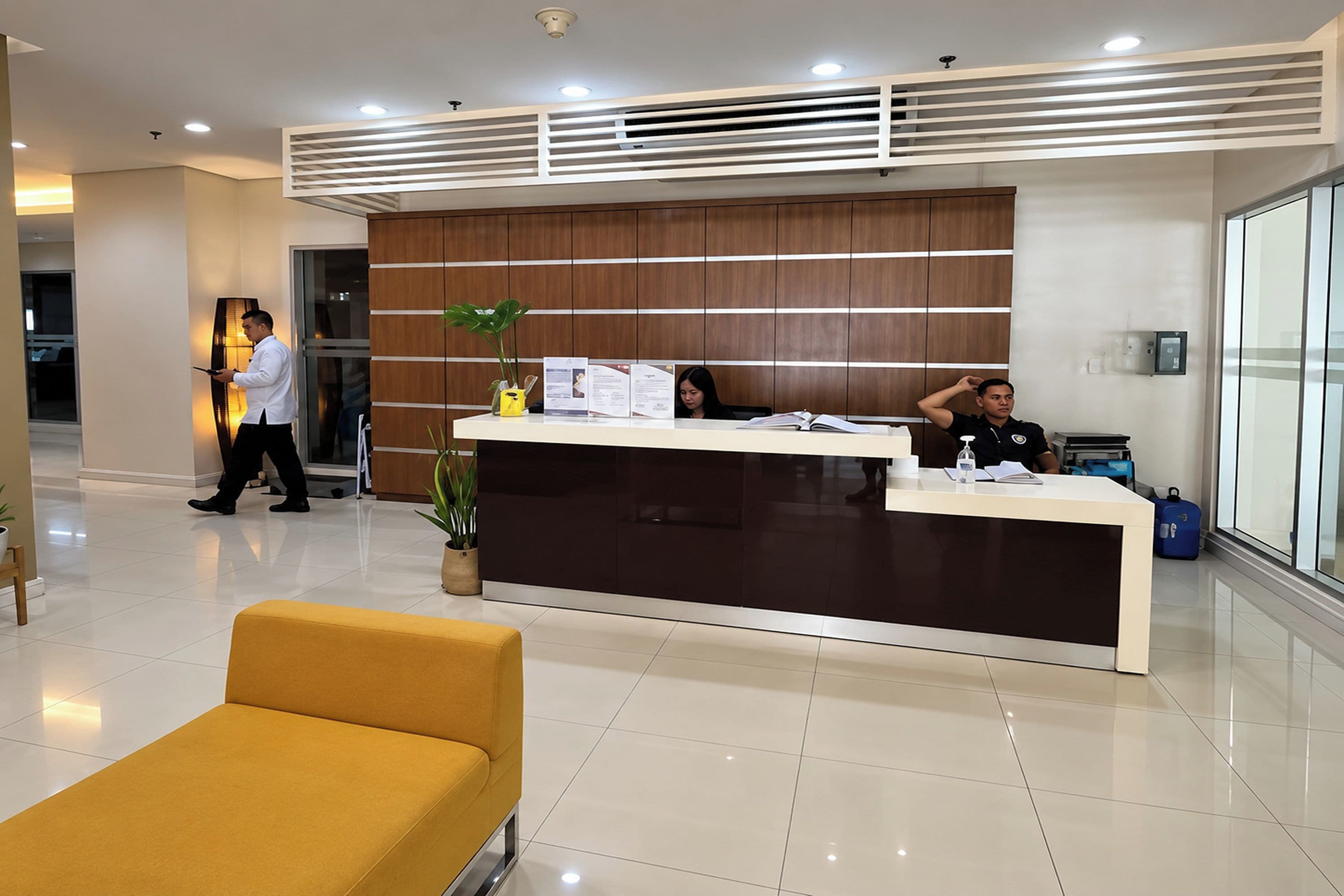 A reception area with a modern design, featuring a reception desk, a yellow armchair, and a potted plant.