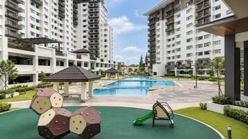 A residential building with multiple floors, a swimming pool, and outdoor play equipment.