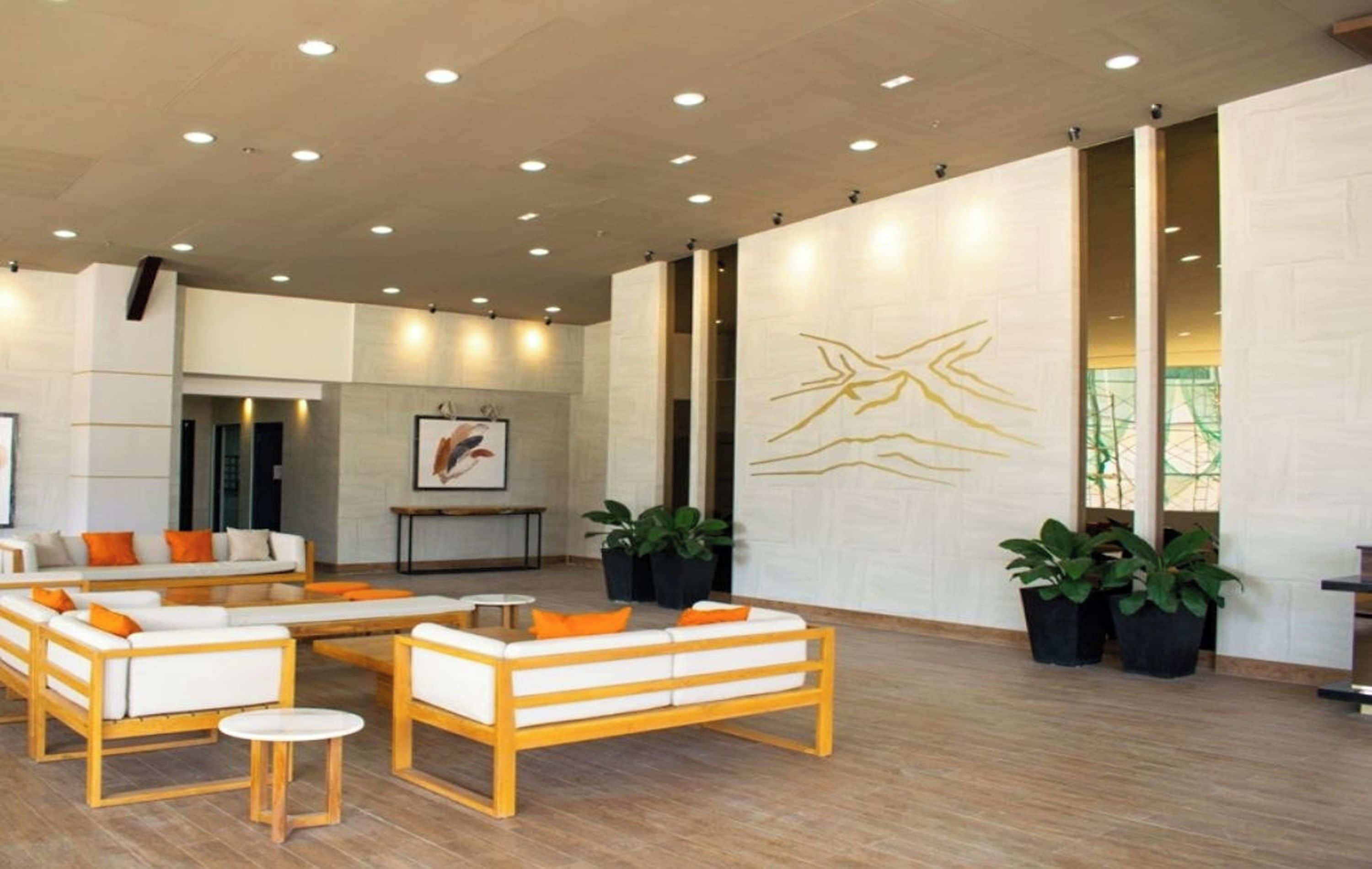 A modern lobby with seating areas, a reception desk, and a large wall art piece.