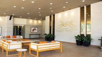 A modern lobby with seating areas, a reception desk, and a large wall art piece.