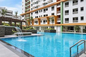 A swimming pool with a waterfall feature, surrounded by a multi-story building with balconies. - Avida Towers Makati West (Makati)