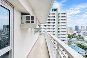A balcony with a city view, air conditioning units, and a tiled floor. - Avida Towers Makati West (Makati)