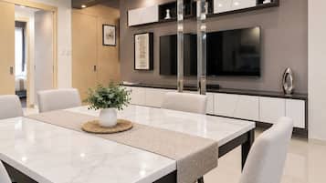 A modern dining area with a marble table, white chairs, a woven placemat, and a potted plant.