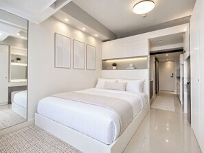 A modern bedroom with a large bed, built-in shelving, and a mirror. - Blowing In The Wind (Tagaytay)