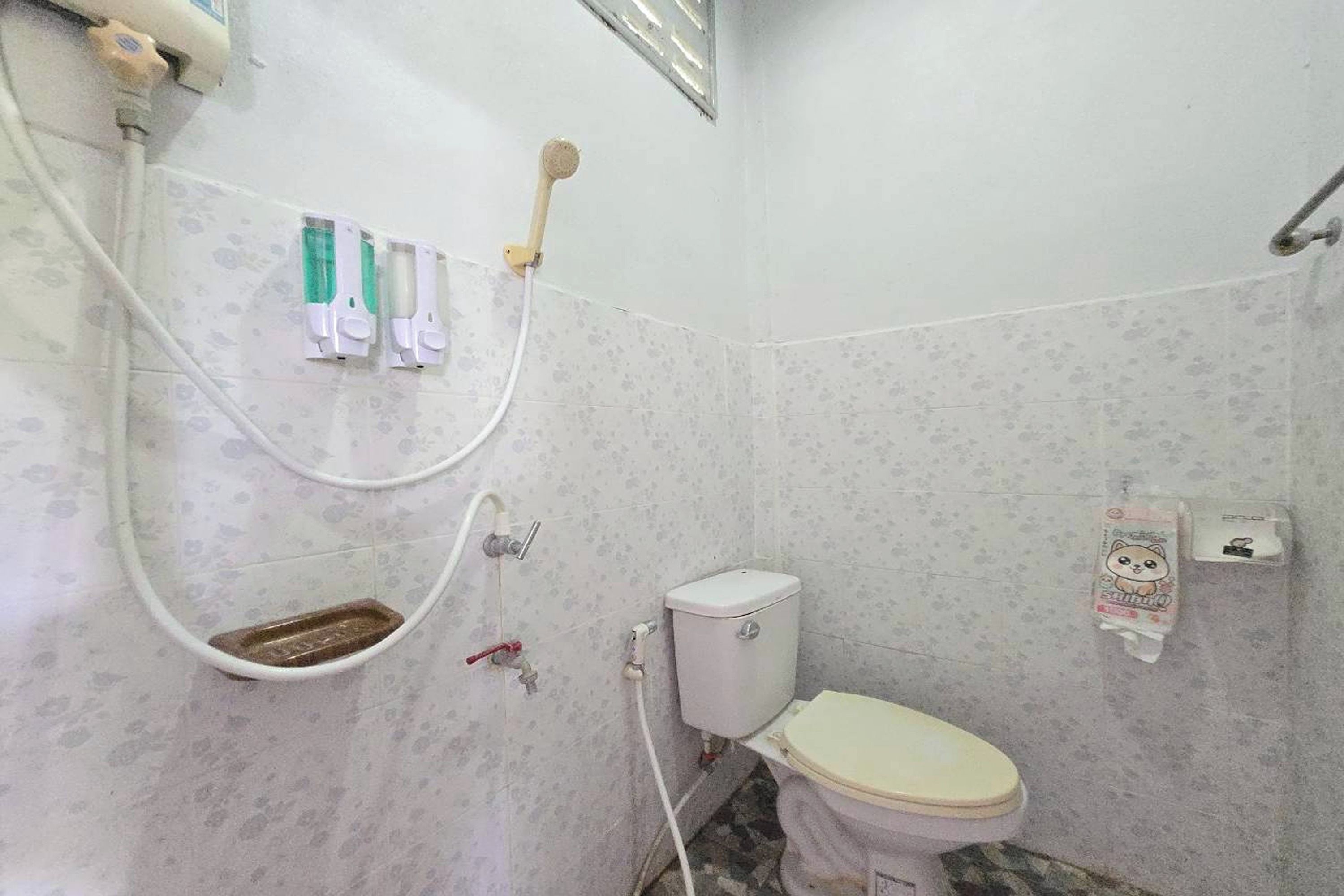 A small bathroom with a toilet, a shower, and a hand dryer.