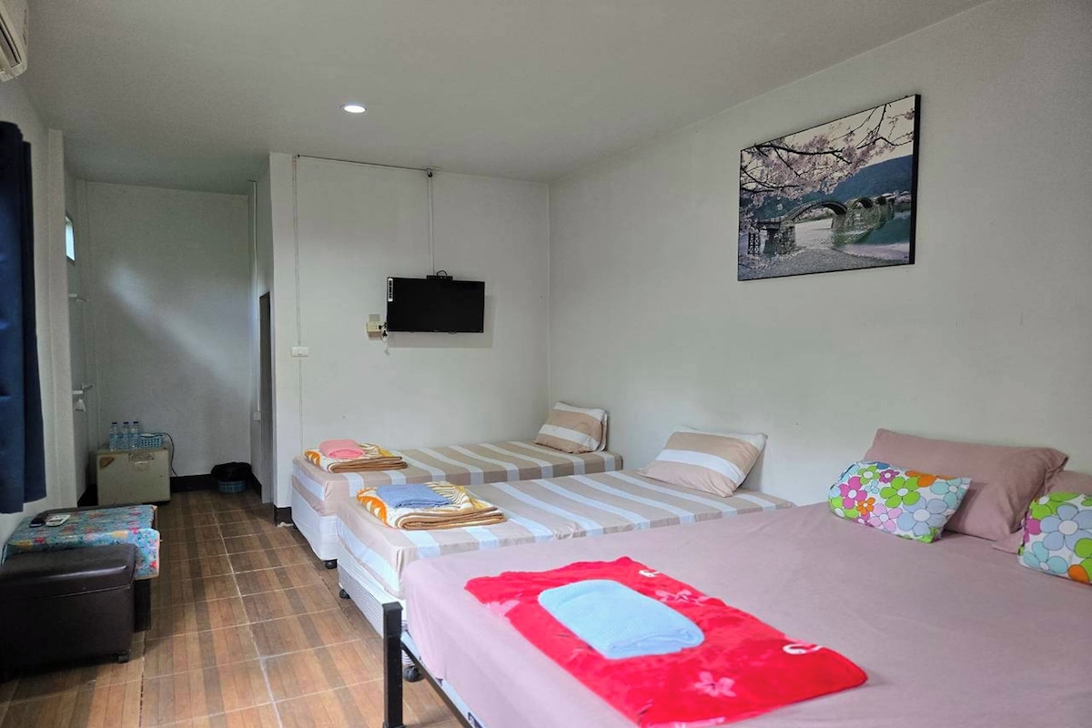 Habitación de hotel con dos camas, un escritorio, una silla, un televisor y un cuadro en la pared.