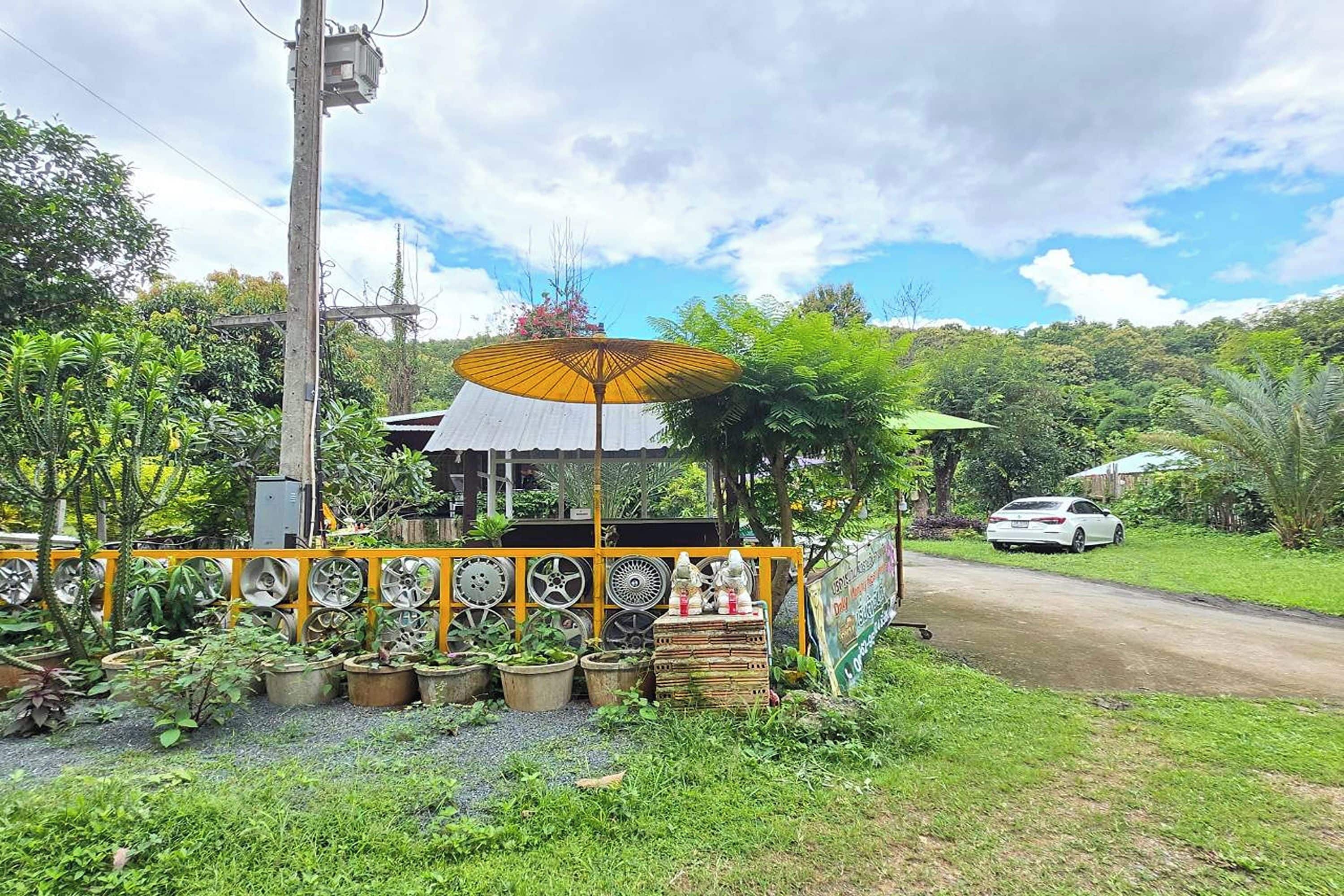 A roadside stall with a yellow fence, wheel rims, and a signboard.