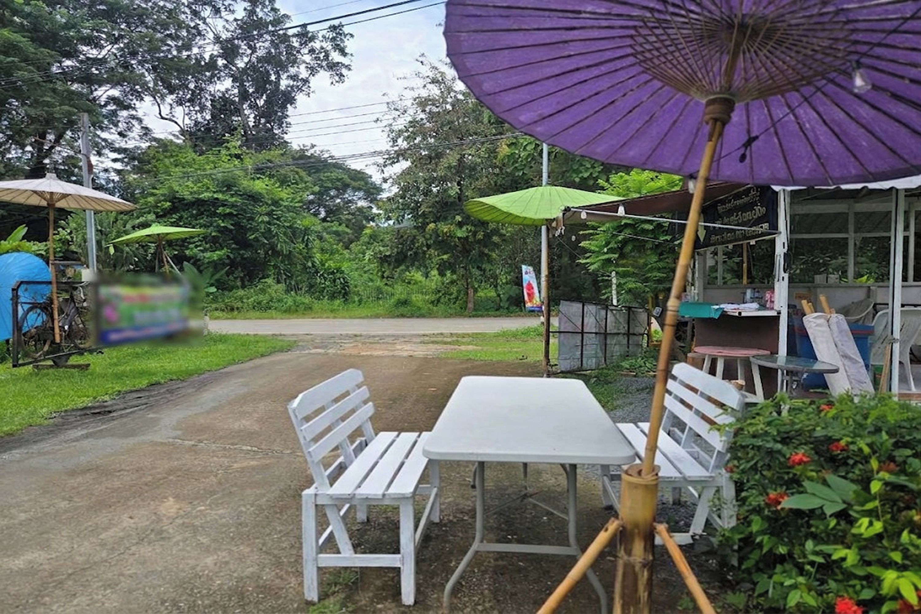 Ein Rastaurant am Straßenrand mit Außenbereich, einschließlich Tisch und Stühlen sowie einem lila Sonnenschirm.