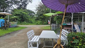 Ein Rastaurant am Straßenrand mit Außenbereich, einschließlich Tisch und Stühlen sowie einem lila Sonnenschirm.