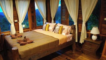 A wooden room with a bed, curtains, and a nightstand.
