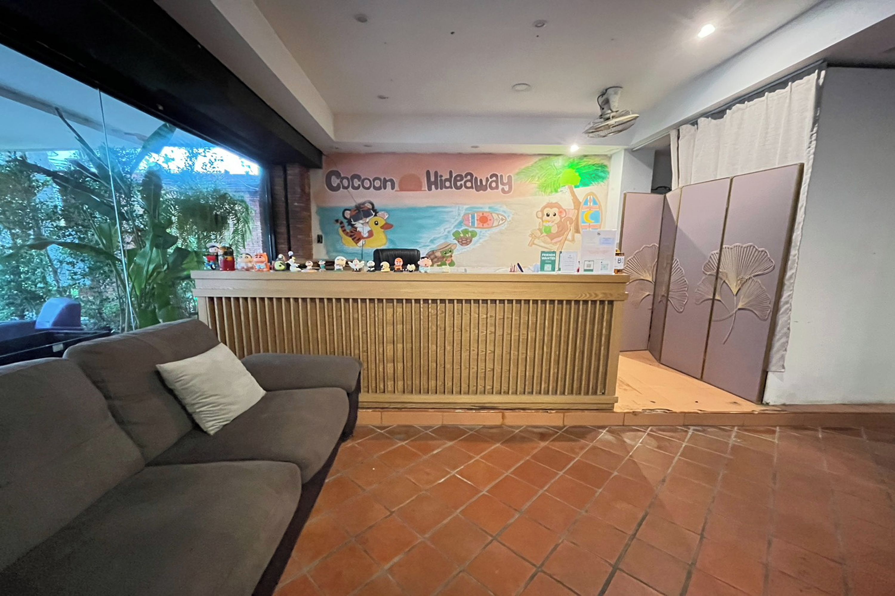 A reception area with a wooden counter, a couch, and a mural depicting a beach scene.